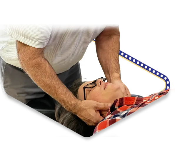 Dr. Dale Kimberlin gently adjusts a patient’s neck while the patient lies on their back during a chiropractic session.