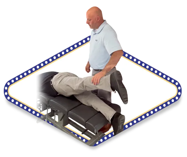 Dr. Dale Kimberlin performs a chiropractic adjustment on a patient lying face down on a treatment table, gently lifting and positioning the patient’s leg to align the lower body.