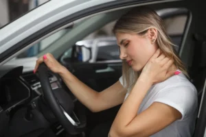 Auto accident whiplash with a female holding her neck in a car