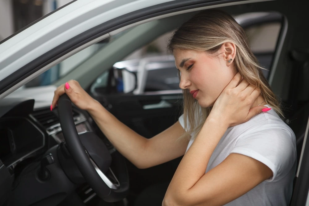 Auto accident whiplash with a female holding her neck in a car