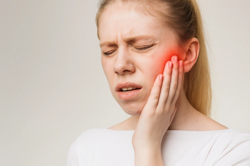 female holding her jaw in pain from TMJ