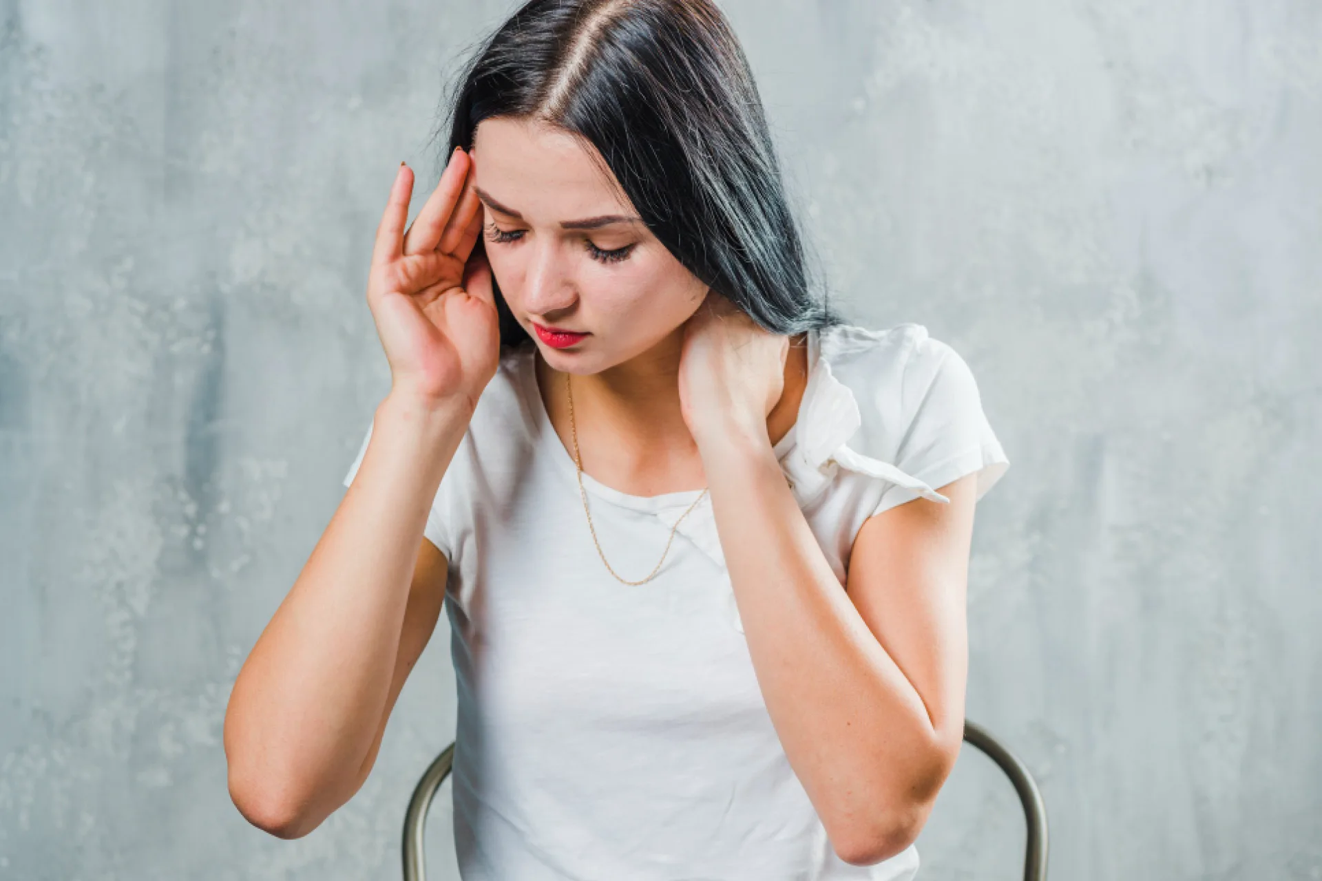 Female holding her head and neck in pain from headaches and migraines