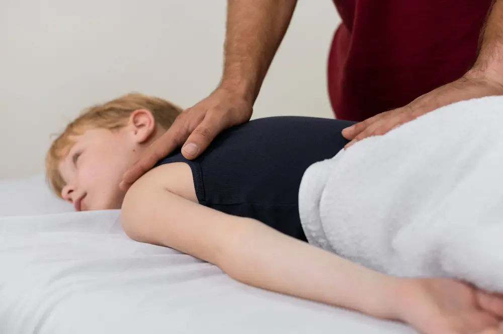 Chiropractor assisting young boy with shoulder pain through pediatric chiropractic care