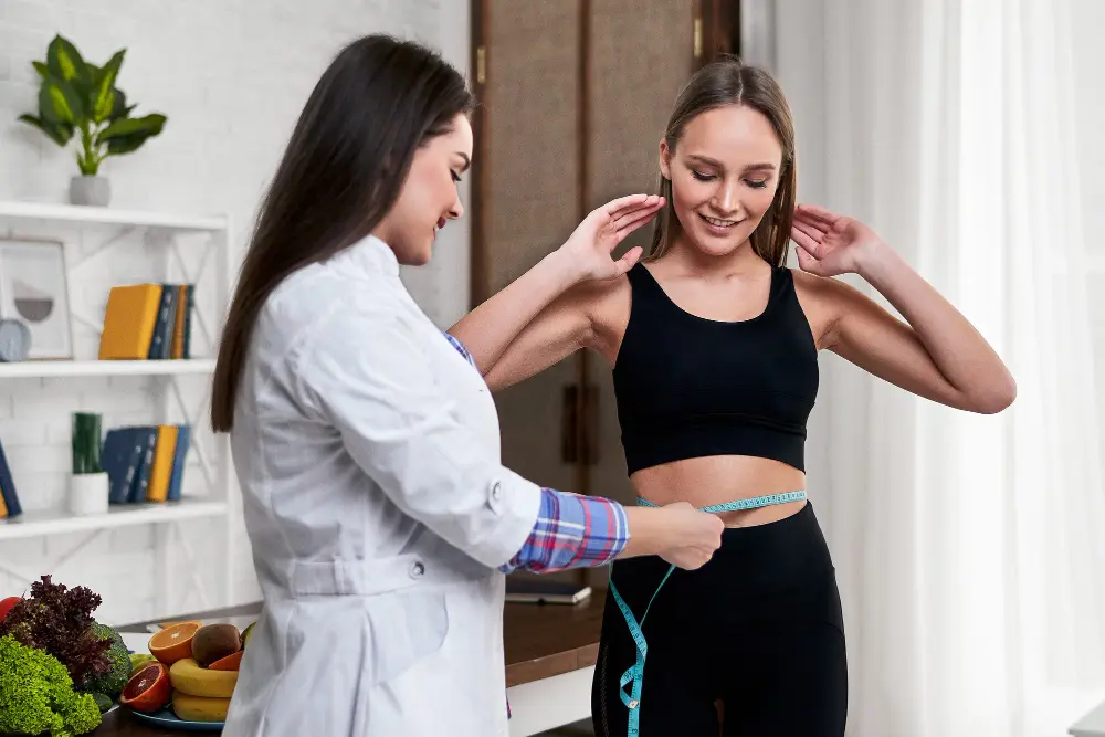 Female chiropractor measuring patient waist during nutritional health assessment