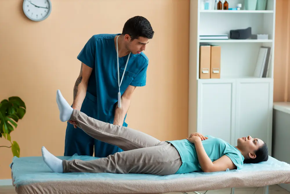 Male chiropractor providing leg therapy treatment to female patient